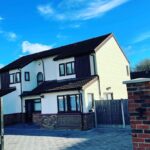 Front of a modern Basildon house with white render, black cladding, and new block paving.